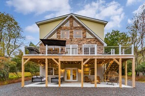 Une maison à deux étages dotée d’un balcon, d’une terrasse en bois et d’une façade en pierre.