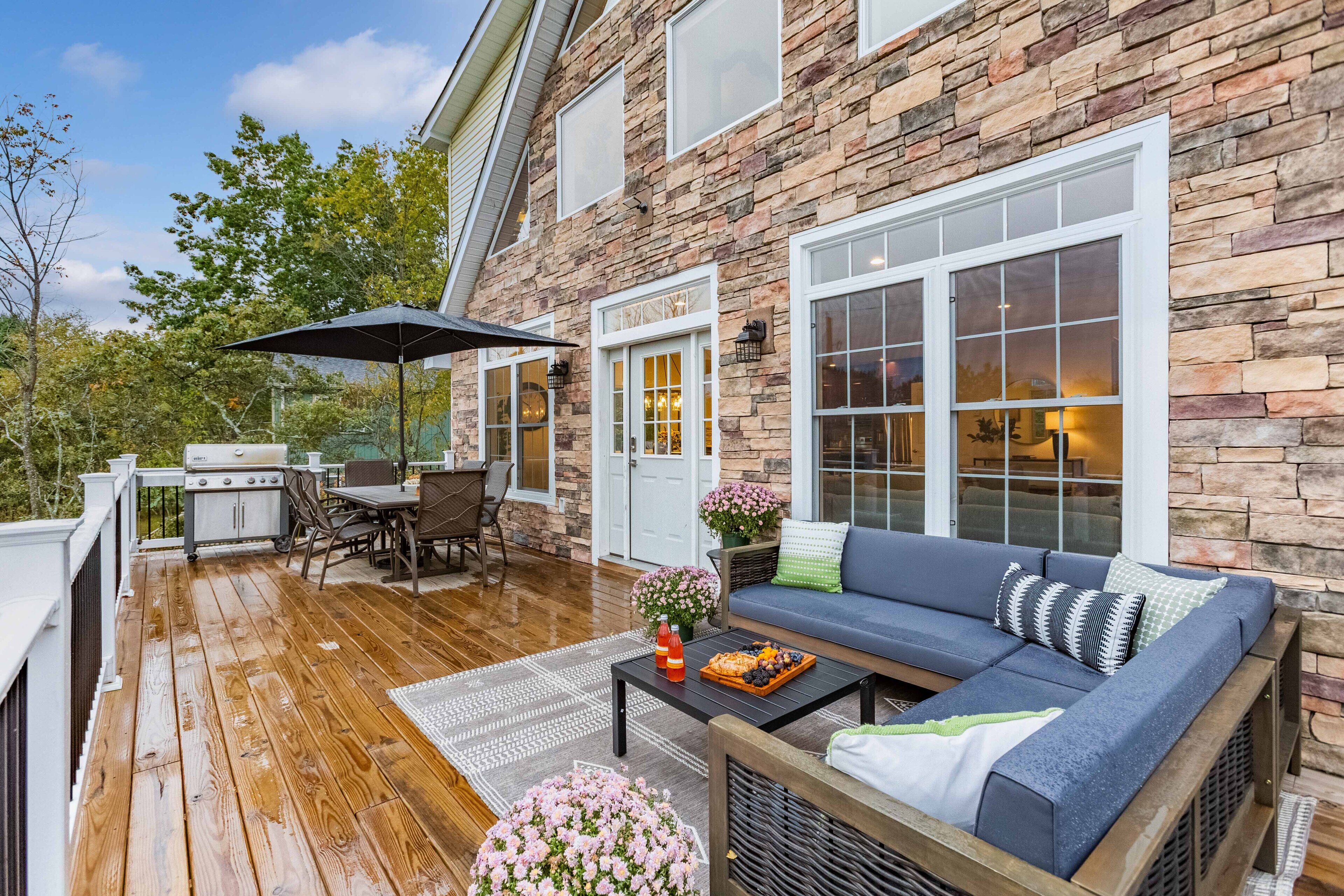 Eine überdachte Terrasse mit Grill, Gartenmöbeln und einer Steinmauer.