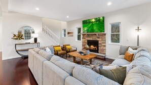 Una sala de estar moderna con chimenea, un sofá grande, una mesa de centro y una escalera.