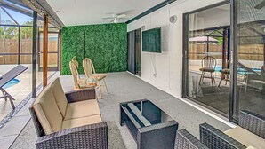 An outdoor patio with wicker furniture, a ceiling fan, and a green wall.