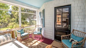 A sunlit porch with wicker furniture, a red carpet, and a view of greenery. - Historic Wolfeboro Home one block to Village (Wolfeboro)