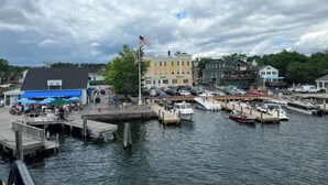 A marina with docked boats, a flagpole with an American flag, and buildings with various storefronts. - Historic Wolfeboro Home one block to Village (Wolfeboro)