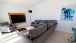 A modern living room with a large flat-screen TV, grey sofas, a coffee table, and a floor lamp. - PREMIUM Apartment with 3 bedrooms. Capacity for 6 people (Marbella)