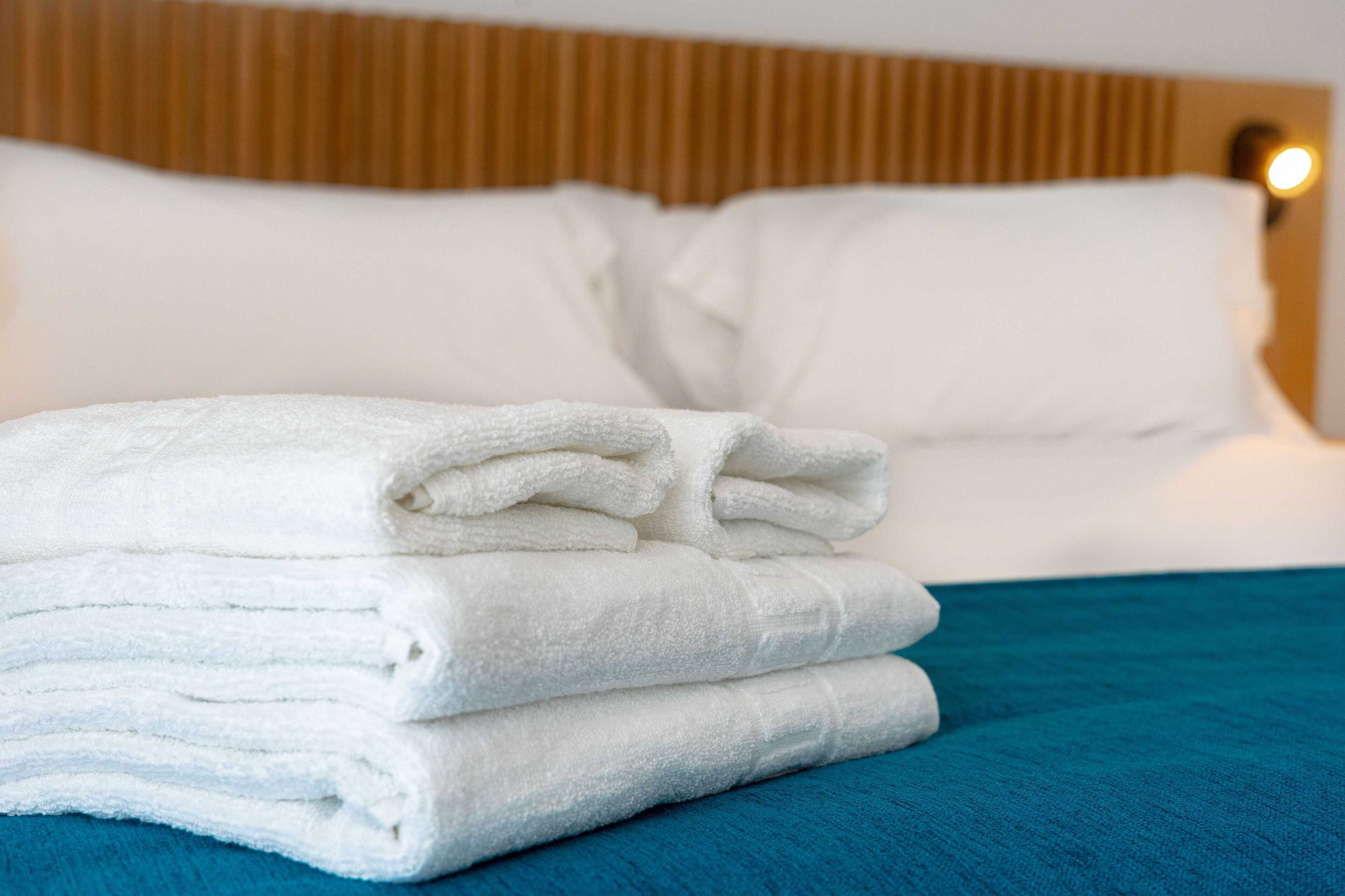 A neatly made bed with white linens and a teal bedspread.