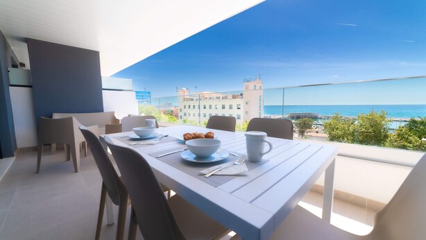 A dining area with a table set for two, overlooking a coastal view. - Deluxe 2 Bedroom Apartment. Capacity for 4 people (Marbella)