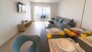A modern living room with a dining area, a sofa, and a table set for breakfast. - Deluxe 2 Bedroom Apartment. Capacity for 4 people (Marbella)