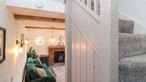 A staircase leading to a landing with a green sofa and a fireplace.