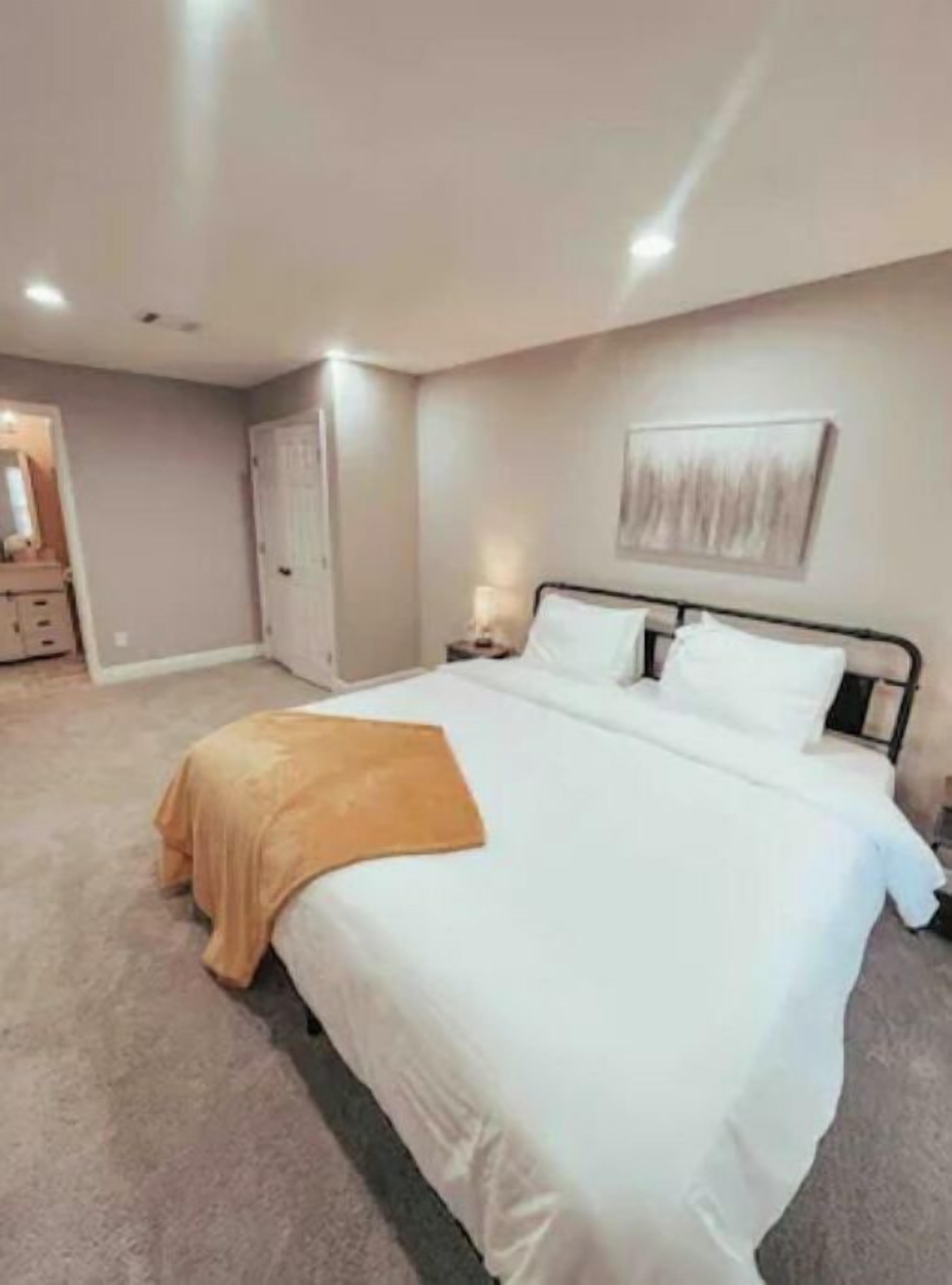 A bedroom with a large bed, a bedside table, a nightstand, a door, and a mirror.