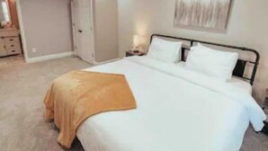 Une chambre à coucher avec un grand lit, une table de chevet, une commode, une porte et un miroir.