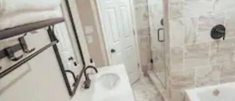 Un baño moderno con ducha de piedra, lavamanos empotrado e inodoro.