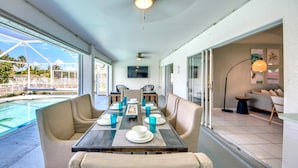 Zona pranzo con vista piscina, ventilatore a soffitto e TV a parete.