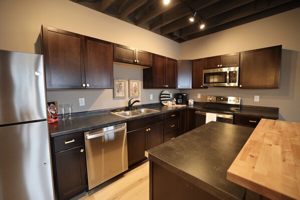 Una cocina moderna con armarios de madera oscura, electrodomésticos de acero inoxidable y encimera de madera.