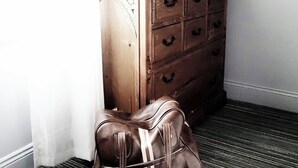 Une commode en bois avec de nombreux tiroirs, un miroir et un vase rempli de fleurs.