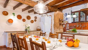 A dining area with wooden chairs and a table set for breakfast, featuring plates of fruit and orange juice. - AINA CAN PONTICO Charming villa in Pollença (Pollença)