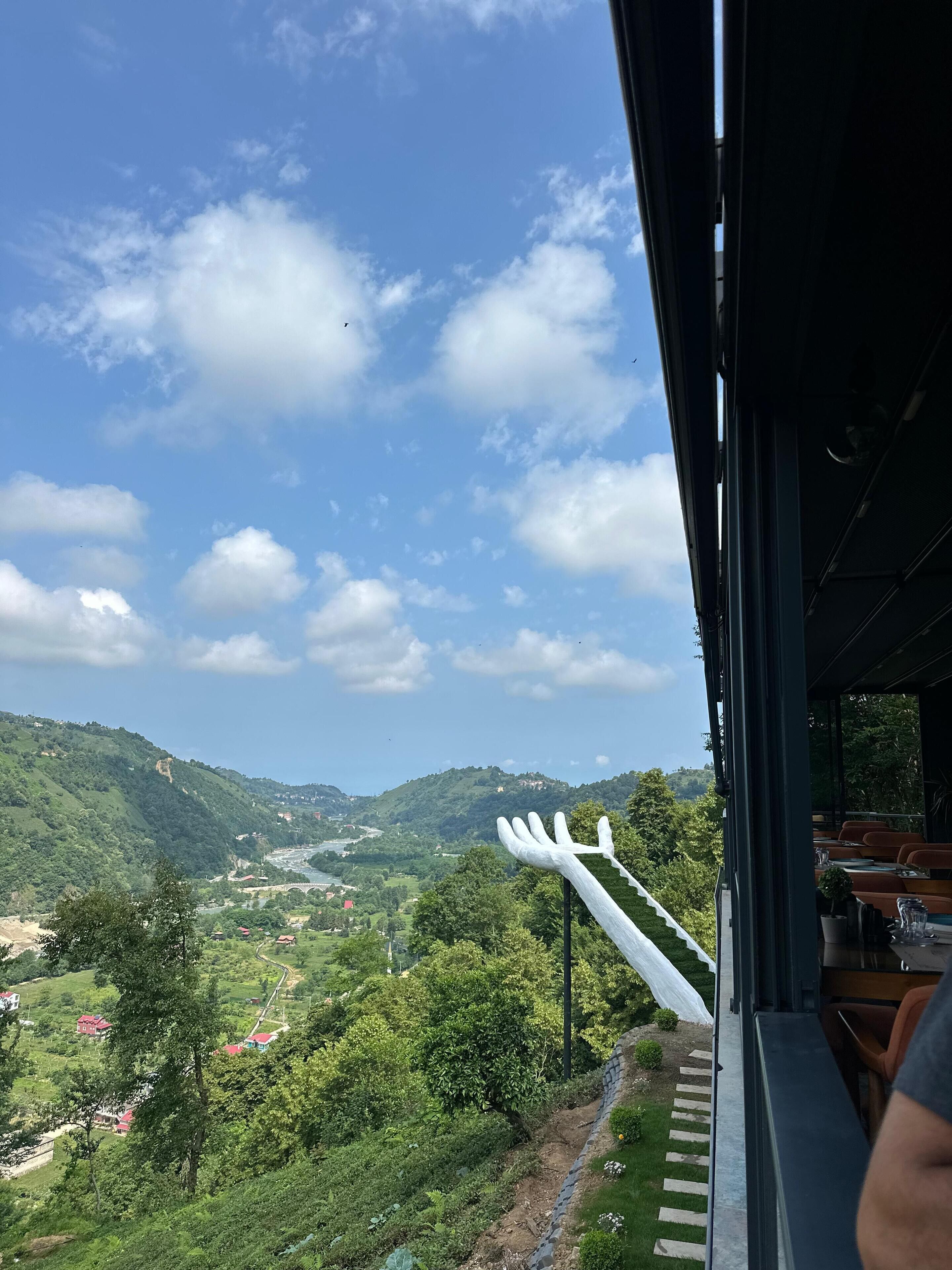 A view from inside a building overlooking a valley with a river, green hills, and scattered houses.