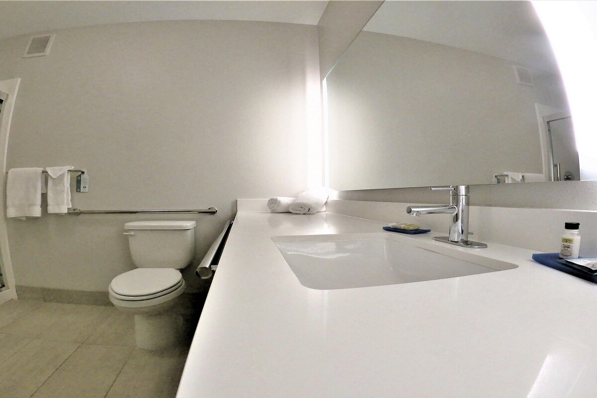 A modern bathroom with a toilet, a shower, and a sink.