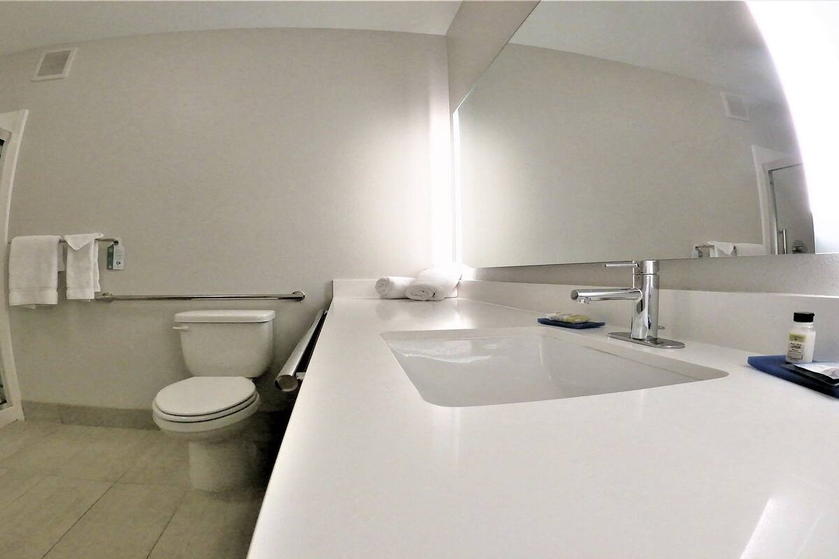 Egy modern fürőszoba, amelyben WC, zuhanyzó és mosdókagyló található.