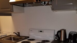 A kitchen with a white stove, a sink, and a kettle. - Le Rameau RC (Montréal)
