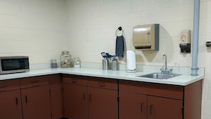 Una cocina compacta con microondas, pileta y alacenas.
