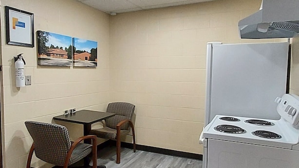 Una kitchenette compacta con estufa, una pequeña mesa de comedor y dos sillas.