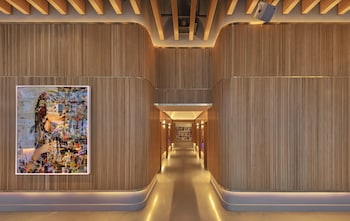 A modern restaurant with round tables, colorful chairs, and large windows offering a view of the city. at Virgin Hotels New York City