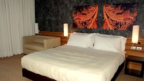 A hotel room with a large bed, a sofa, two wall-mounted lamps, and coral-themed artwork. - Sea Art Hotel (Vado Ligure)