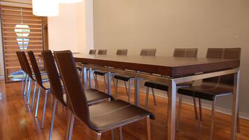 Un salón de conferencias con una larga mesa, varias sillas y una lámpara de araña moderna.