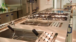 A commercial kitchen with stainless steel appliances, including a range, sink, and fryer. - Sea Art Hotel (Vado Ligure)