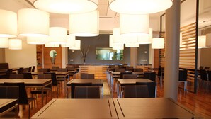 A modern restaurant with multiple dining tables and chairs, large pendant lights, and a wooden interior. - Sea Art Hotel (Vado Ligure)