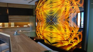 A modern kitchen with a wooden countertop and a large, abstract yellow and orange wall art piece. - Sea Art Hotel (Vado Ligure)