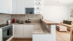 Een moderne keuken met witte kastjes, een marmeren aanrechtblad en een ingebouwde oven.
