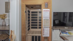 A sauna room with wooden walls and a control panel, a television, and informational posters on the wall.