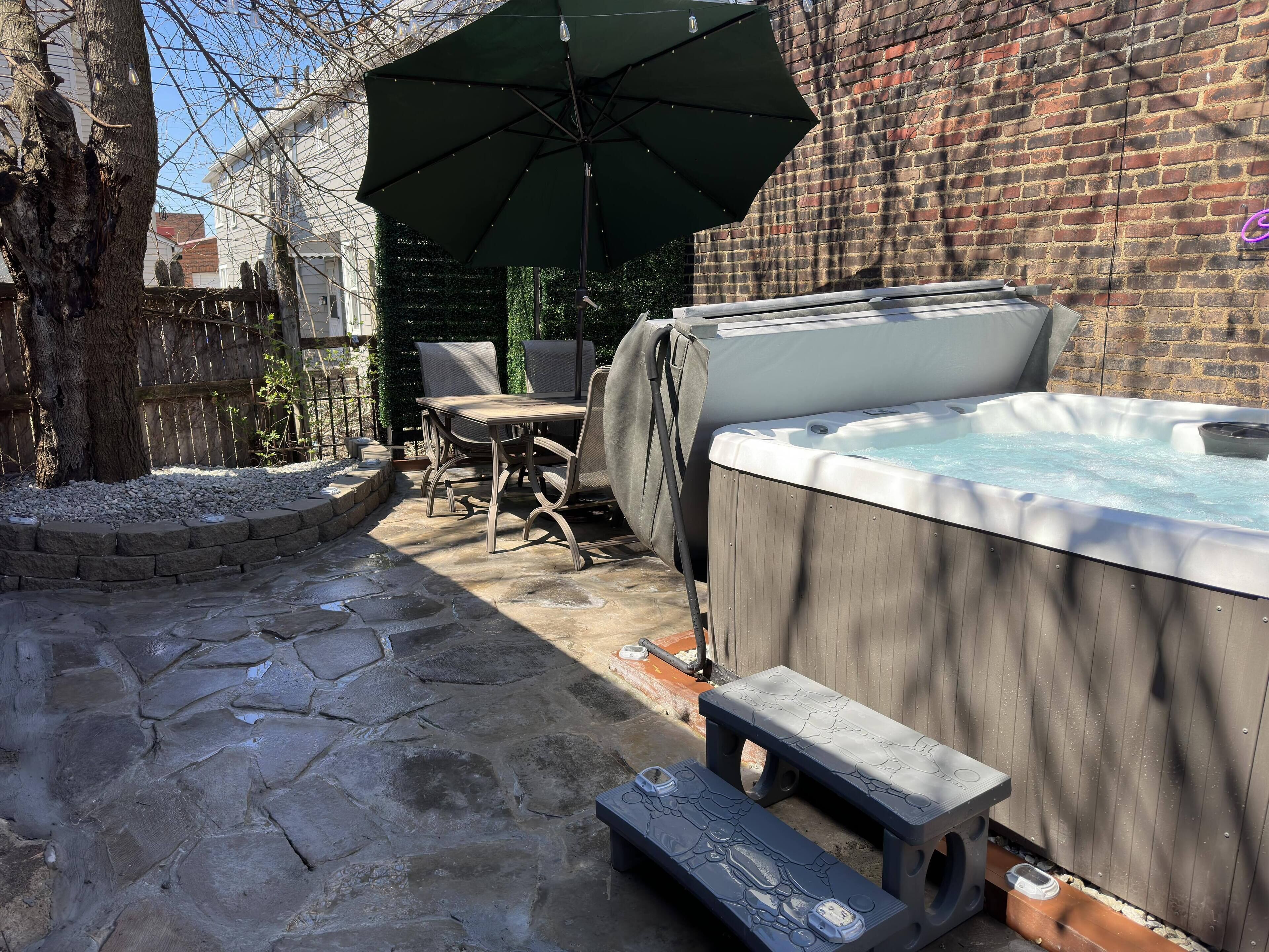 A patio area with a hot tub, outdoor furniture, and a stone pathway.