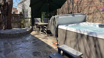 A patio area with a hot tub, outdoor furniture, and a stone pathway.