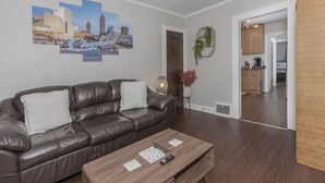 A living room with a brown leather sofa, a wooden coffee table, and a cityscape mural on the wall.