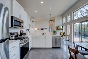 A modern kitchen with white cabinetry, stainless steel appliances, and a large island.