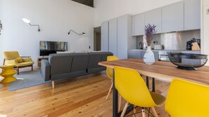 A modern living room with a grey sofa, yellow chairs, and a wooden dining table.