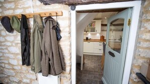 A rustic stone wall with hanging coats and a wooden coat rack. - Beautiful Cotswolds Cottage & Garden (Horsley)