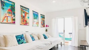 Quarto moderno com sofá branco, uma mesinha e uma rede perto da janela.