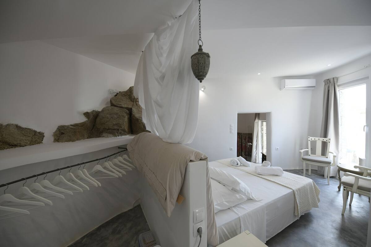 Een moderne hotelkamer met een groot bed, een hanglamp en uitzicht op de omgeving.