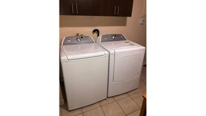 A laundry area with two white washing machines and a dark wooden cabinet above them. - The Rameau 1er (Montréal)