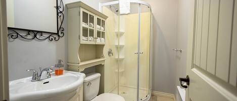 A bathroom with a white sink, toilet, and glass-enclosed shower.
