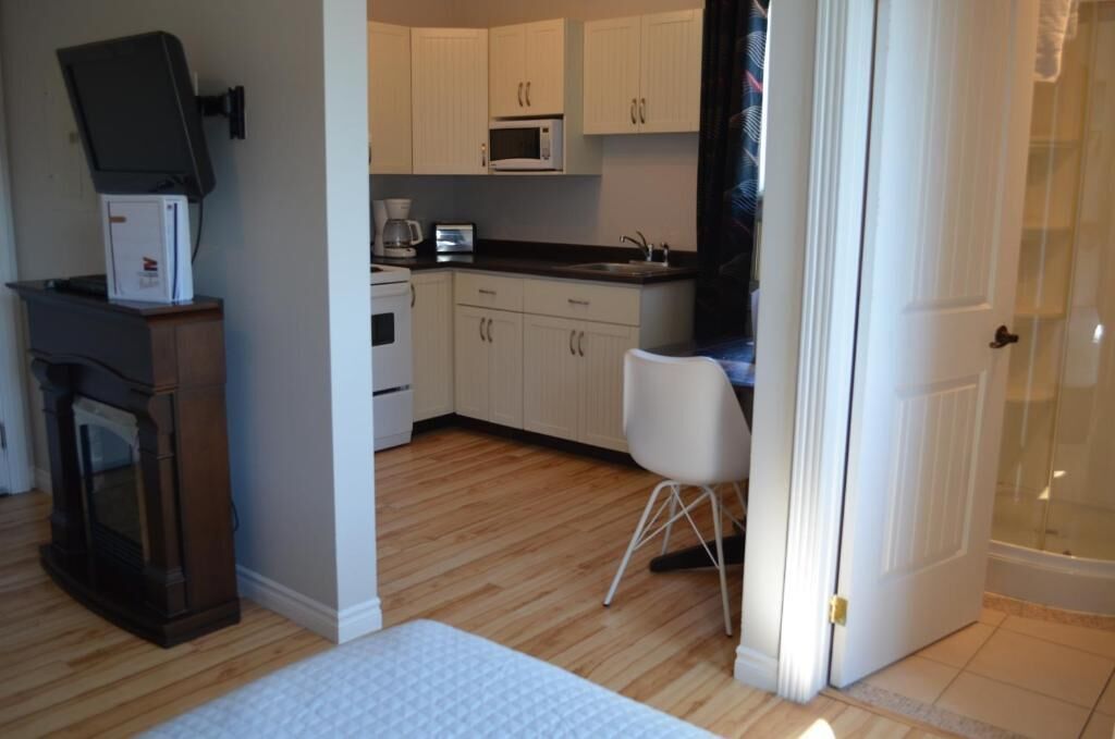 A compact living space with a kitchenette, a fireplace, and a white chair.