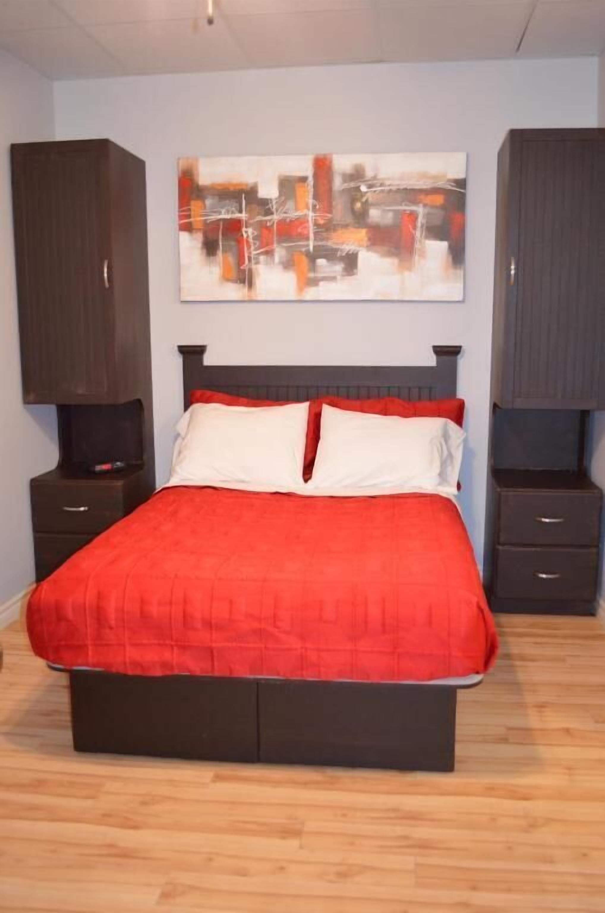 A bedroom with a bed, two nightstands, a wall-mounted TV, and a piece of abstract art.