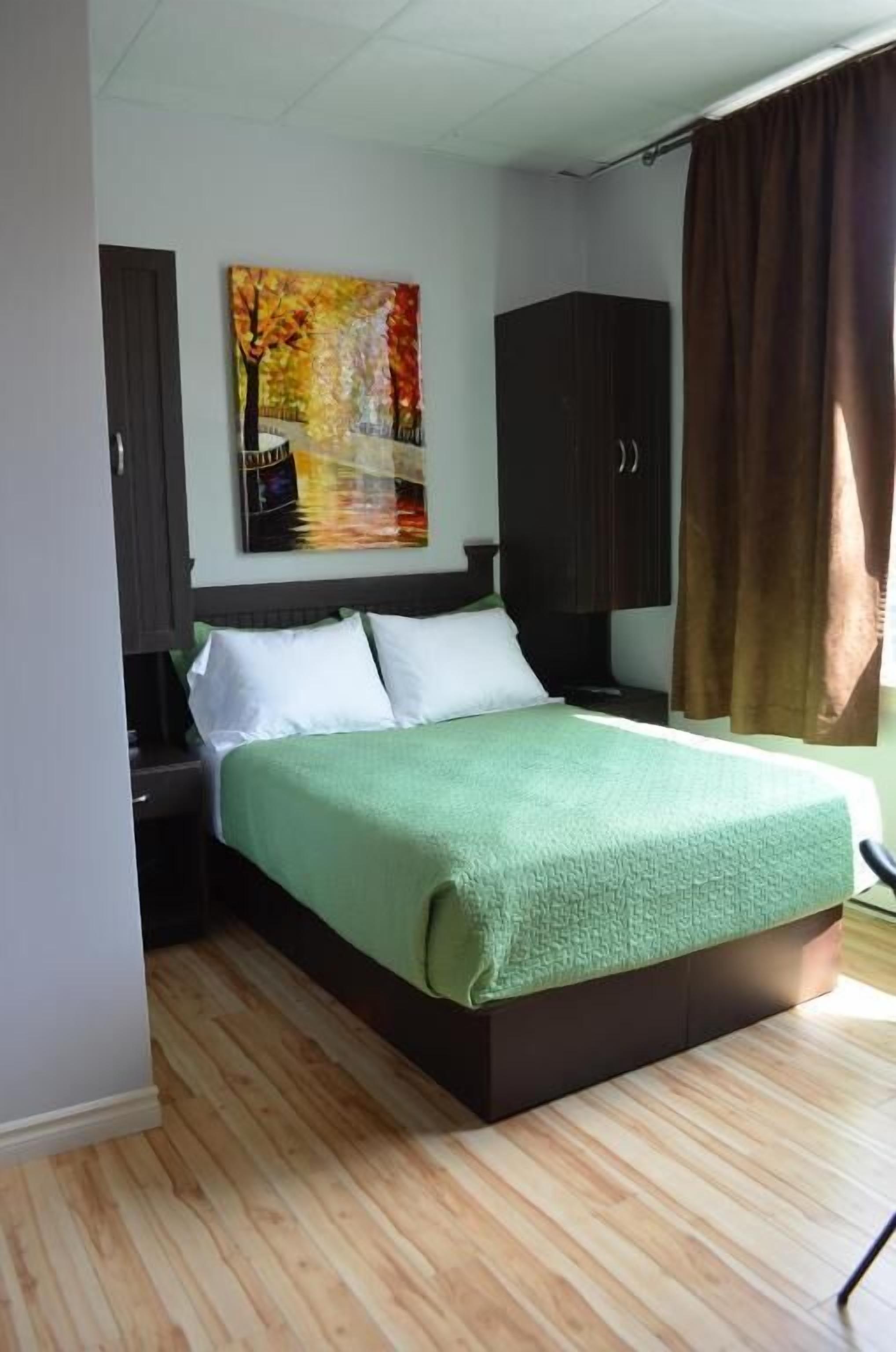 A bedroom with a bed, a nightstand, a wardrobe, and a painting on the wall.