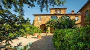 A stone building with a central courtyard, surrounded by lush greenery and potted plants. - Villa Gagnoni for 10p with private pool and large garden; airco in all bedrooms. (Sinalunga)