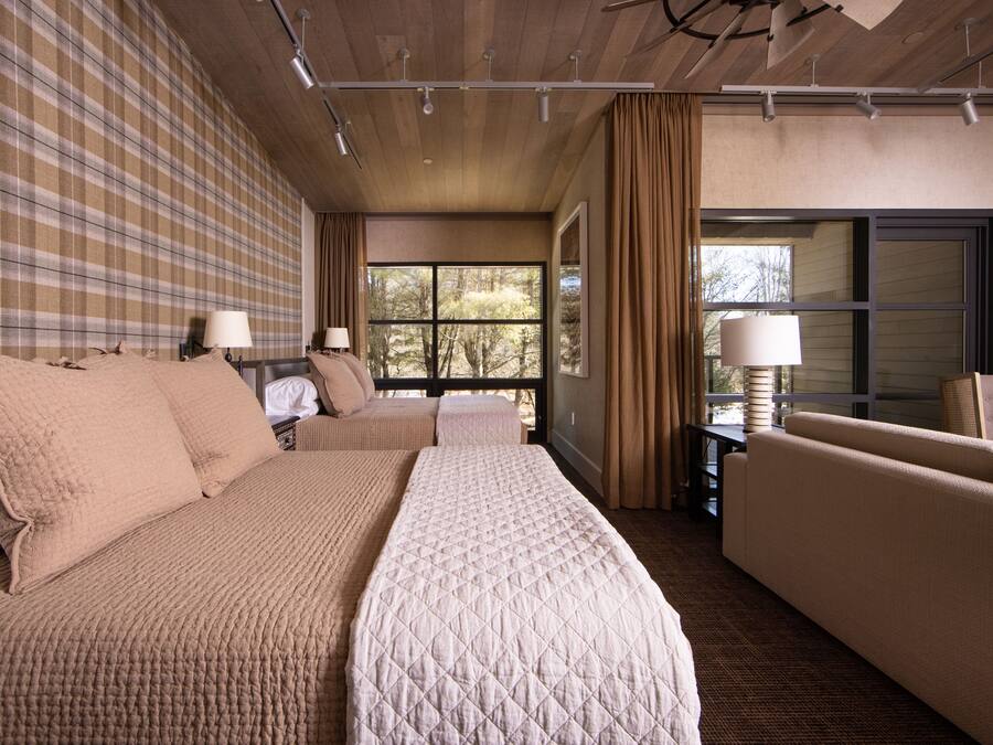 Una habitación de hotel con una cama grande, dos sofás, una mesita y una ventana con cortinas.