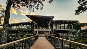 Un bâtiment moderne doté d’une passerelle en bois menant à une entrée abritée.
