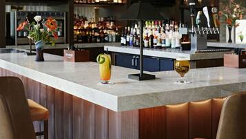 Una zona de bar con una encimera de mármol, un jarrón con flores y dos vasos de bebidas.