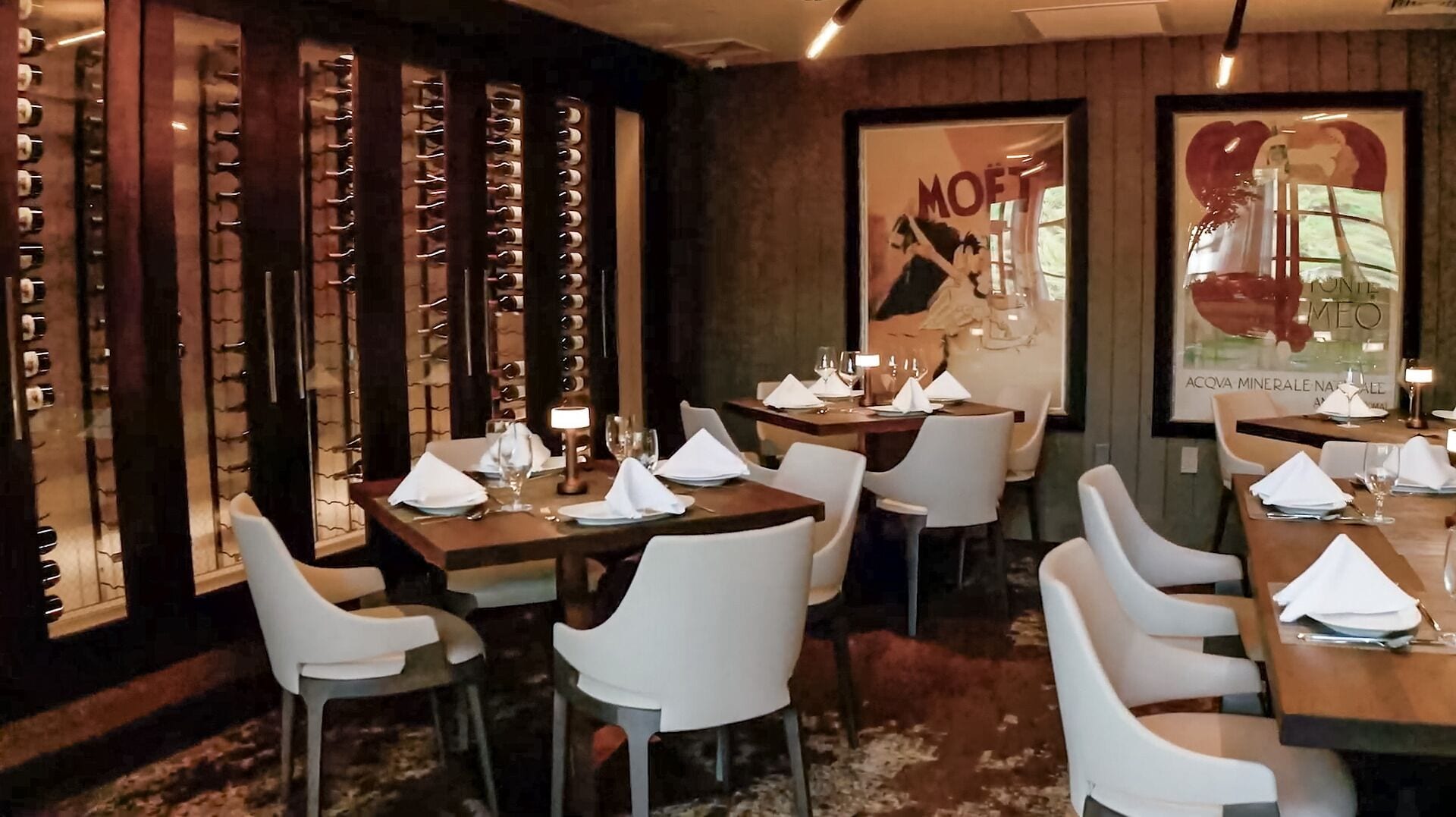 Ein Restaurantinneres mit Holzwänden, weißen Stühlen und für das Essen gedeckten Tischen.
